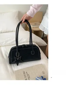Detail of black leather shoulder bag with white contrast stitching and star charm