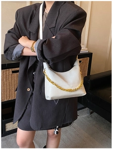 Detailed view of white high-gloss leather shoulder bag with gold chain on model