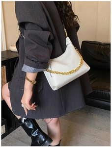 Close-up of white leather hobo bag with textured finish and thick gold metal chain strap