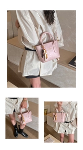 Detail showing pink faux leather bucket bag with colorful beaded charm and top handles