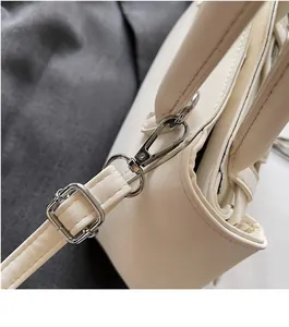 Detail shot of silver metal swivel hook and adjustable strap on a beige handbag