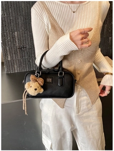 Détail du sac Boston en cuir noir avec doubles poignées et adorable pendentif ourson