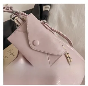 Gros plan sur un mini sac enveloppe en cuir rose avec cordon tressé et anneau argenté