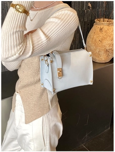 Detail of light blue faux leather handbag with gold twist lock and metal rivet accents