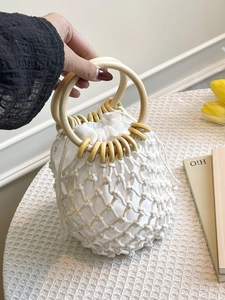 White woven cotton rope handbag with round wooden handles and drawstring inner bag