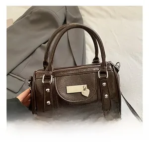 Detail view of glossy brown vintage bowling bag with heart charm and metal hardware