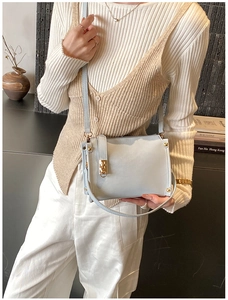 Close-up of light blue matte shoulder bag with gold hardware on a stylish model