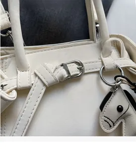Close-up of white leather handbag with silver buckle and leather pony charm detail