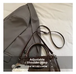 Detail of glossy brown bowling bag showing the adjustable strap and cute alpaca charm