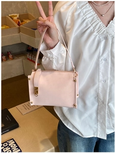 Detail of light pink PU leather handbag with golden hardware and twist lock closure