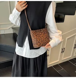 Détail du sac seau à imprimé léopard avec bandoulière en similicuir porté par un modèle