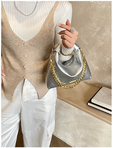 Detail of silver hobo bag featuring a metallic crinkle texture and gold chunky chain strap