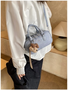 Détail du sac bowling lilas en cuir grainé avec charme d'ours et logo gravé