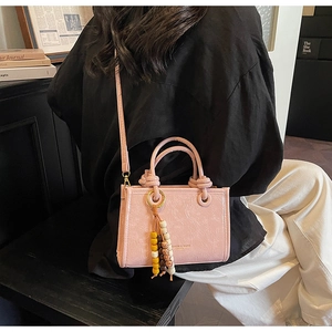 Detail of pink crossbody bag with colorful wooden beads tassel and fashion branding