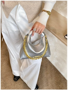 Detail of silver metallic hobo bag with a chunky gold chain strap on model shoulder