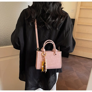 Rear view of model wearing a pink leather bucket bag with colorful beaded tassel detail