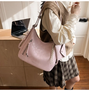 Détail du grand sac hobo rose clair avec pompon et détail de nœud latéral tissé