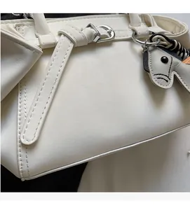 Detailed close-up of white leather tote bag with silver buckle and zebra horse charm
