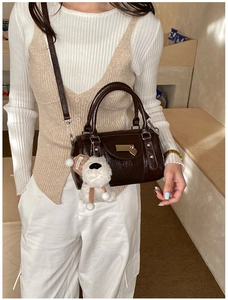 Detail of dark brown vintage bowling bag with polished finish and dog plush charm
