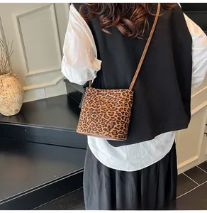Détail d'un petit sac bandoulière à motif léopard avec une fine bandoulière en cuir brun