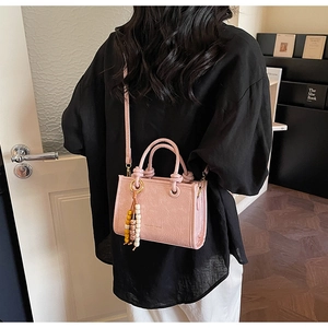 Pink pleated leather bucket bag with wooden beads shown on a model in a cozy setting
