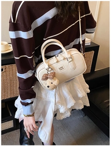Détail du sac Boston beige avec charm ourson porté par un mannequin en décor chic