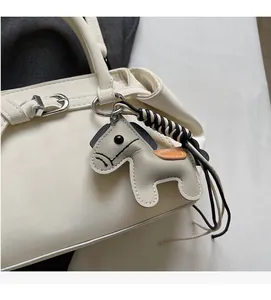 Close-up of white leather tote bag featuring a grey leather horse charm with stitching