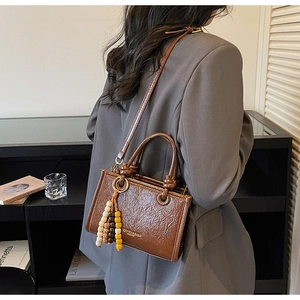 Chic coffee brown bucket bag with beaded tassel shown in a professional lifestyle setting