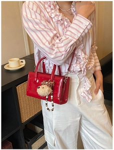 Detail of red glossy mini box bag with plush bear charm and beaded chain accessory