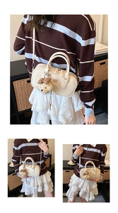 Détail du sac bowling en cuir beige avec charm ours en peluche et décoration de nœud