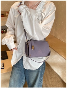 Detail of lavender textured crossbody bag with gold stud accents and snap buckle