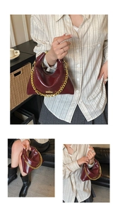 Close-up of wine red glossy chain bag with unique triangular structure and gold chain strap