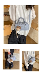 Détail du sac Boston bleu clair avec logo embossé et breloque ours en peluche marron