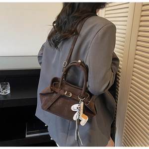Detail of dark brown suede shoulder bag with belt buckle and horse charm on a model