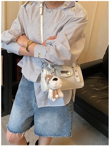 Off-white mini Boston bag featuring a cute plush dog charm on a striped shirt outfit