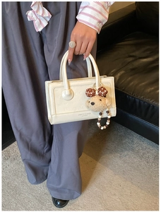 Detail of cream leather handbag with bear charm and Fashion & Bags text logo