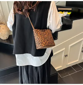 Sac seau à motif léopard présenté en situation avec une fine bandoulière marron