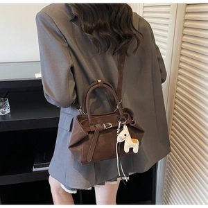 Detail of dark brown matte tote bag with horse charm and adjustable strap shown on model