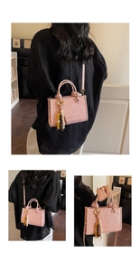 Detailed view of a pink bucket bag with beaded tassel and adjustable shoulder strap