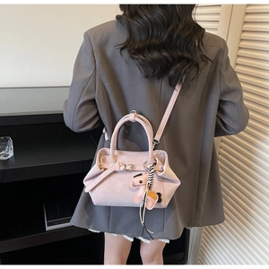 Detail of minimalist pink handbag with metal buckle, charm and slim shoulder strap