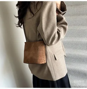 Détail du sac à bandoulière en daim givré marron avec fine bandoulière et design minimaliste