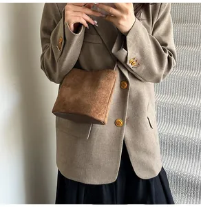 Détail du sac bandoulière en daim marron foncé avec base cylindrique et fine bandoulière