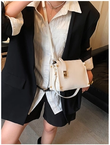 Minimalist white shoulder bag with gold turn-lock and studs styled on a blazer