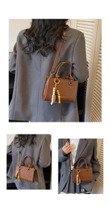 Detail view of brown leather bucket bag with beaded tassel and detachable strap