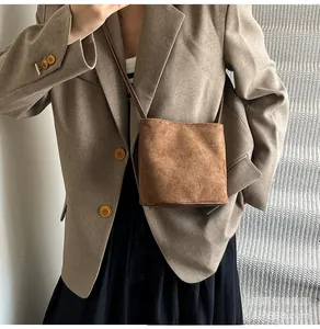 Mini sac seau en cuir mat marron porté avec un blazer pour un style vintage chic