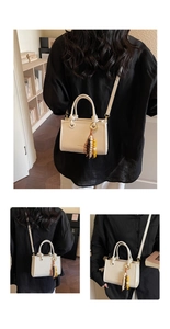 Detail of off-white leather crossbody bag with wooden bead tassel and gold logo