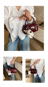 Detail of burgundy leather Boston bag with plush puppy pendant and heart charm