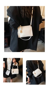 Detail of white rectangular crossbody bag with gold twist lock and adjustable shoulder strap