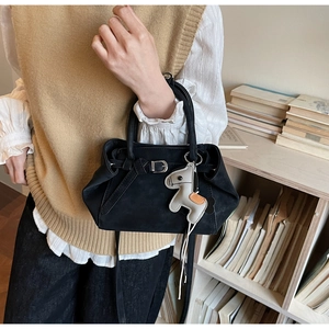 Close-up of black matte suede tote bag featuring a cute horse charm and metal buckle details