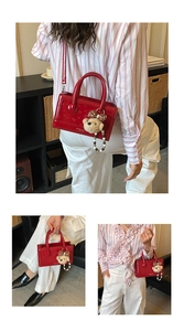 Detail of red embossed handbag with plush bear charm and detachable shoulder strap